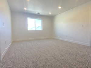 Carpeted spare room with baseboards and recessed lighting