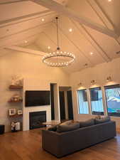 Living area with dark wood-type flooring, a glass covered fireplace, and hanging lights