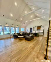 Living area featuring a high ceiling, light wood-type flooring, plenty of natural light, and recessed lighting