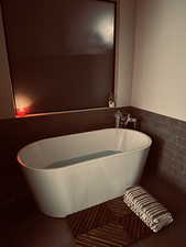 Bathroom featuring a freestanding bath, tile walls, wainscoting, and tile patterned floors