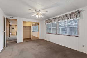 Unfurnished bedroom with carpet flooring, a closet, ceiling fan, and a textured ceiling