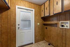 Laundry area with hookup for a washing machine, wooden walls, cabinet space, and electric dryer hookup