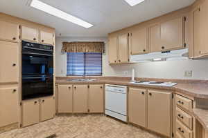 Kitchen featuring white appliances, light countertops, and cream cabinets