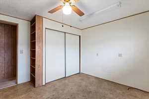 Unfurnished bedroom with wood walls, ceiling fan, a textured ceiling, tile patterned floors, and a closet