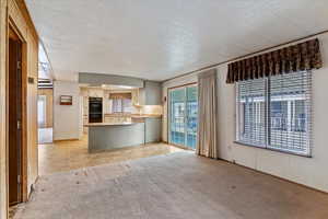 Kitchen with light countertops, open floor plan, light carpet, a peninsula, and cream cabinets