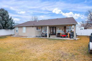 Back of house with a fenced backyard, a shingled roof, stucco siding, and a patio area