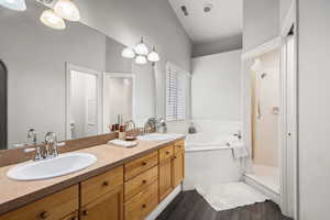 Full bath with double vanity, a garden tub, a shower stall, and dark wood-type flooring