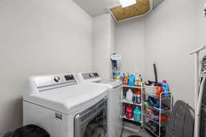 Laundry room with a textured wall, washing machine and clothes dryer, and a textured ceiling