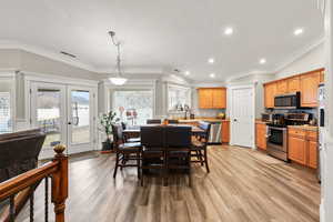 Dining space featuring french doors, light wood-style floors, recessed lighting, and crown molding