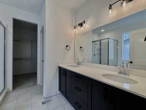 Bathroom featuring double vanity, a stall shower, and a spacious closet