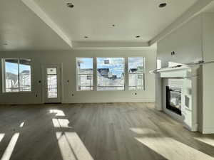 Unfurnished living room featuring light wood-style floors and a glass covered fireplace