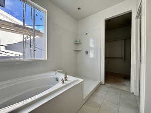Full bath featuring a bath, a spacious closet, and a walk in shower