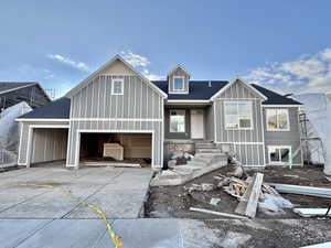 View of front of home featuring a shingled roof, concrete driveway, and board and batten siding
