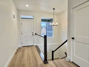 Foyer featuring light wood finished floors and hanging lights
