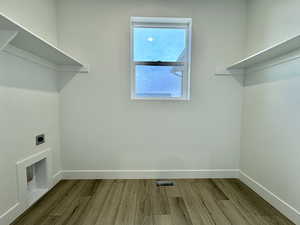 Laundry area with light wood-type flooring and hookup for an electric dryer