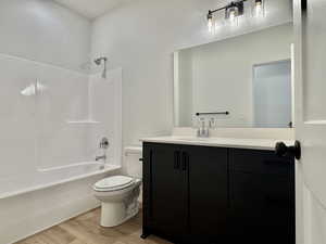 Full bath with vanity, light wood finished floors, and shower / washtub combination