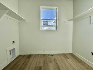 Laundry room featuring wood finished floors and electric dryer hookup