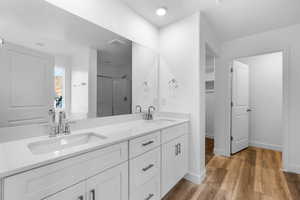 Bathroom featuring a stall shower, double vanity, light wood-style flooring, and a walk in closet