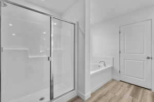 Full bath with a stall shower, a bath, and light wood-style floors