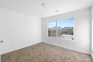 Carpeted spare room featuring baseboards