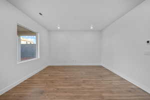 Empty room with light wood-style floors and recessed lighting