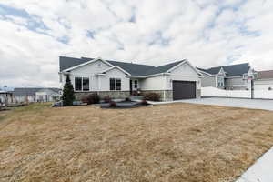 View of front of home with stone siding, driveway, an attached garage, roof with shingles, and board and batten siding