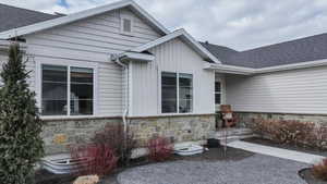 View of exterior entry with roof with shingles and stone siding