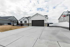 View of front facade with stone siding, concrete driveway, and a garage