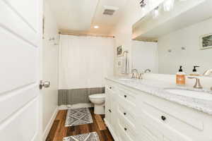 Bathroom with a shower with curtain, double vanity, dark wood-style flooring, and recessed lighting