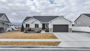 View of front of home with stone siding, concrete driveway, a garage, board and batten siding, and roof with shingles