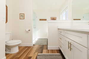 Full bath featuring a shower stall, vanity, and dark wood-type flooring
