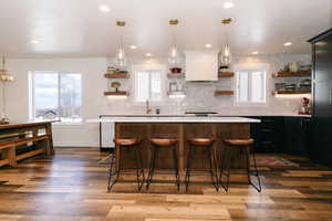 Kitchen featuring decorative light fixtures, open shelves, a kitchen breakfast bar, and dark wood-type flooring