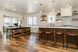 Kitchen featuring decorative light fixtures, light wood-style floors, open shelves, and tasteful backsplash