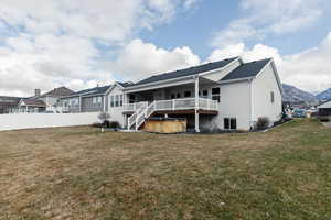 Rear view of house with a deck with mountain view and a hot tub