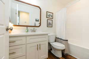 Full bathroom with vanity, dark wood-type flooring, and shower / bathtub combination with curtain