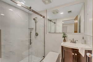 Bathroom featuring vanity, a marble finish shower, and recessed lighting