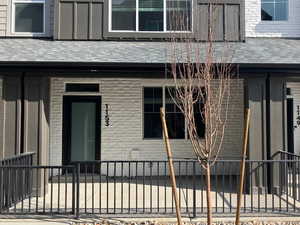 Property entrance featuring brick siding and a shingled roof