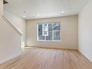 Unfurnished room with light wood finished floors, recessed lighting, and a textured ceiling