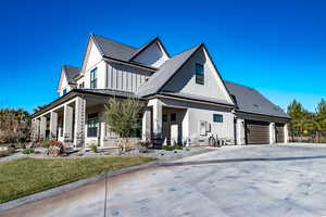 Modern farmhouse featuring a large porch, concrete driveway, a standing seam roof, a garage, and board and batten siding