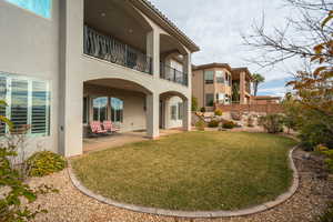 Rear view of house with stucco siding, a balcony, a patio, and a tiled roof