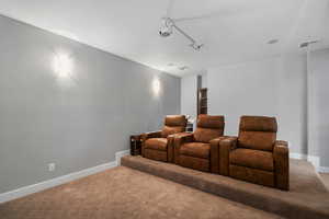 Carpeted home theater featuring baseboards