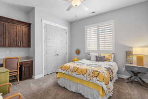 Bedroom with built in desk, light colored carpet, a closet, and ceiling fan