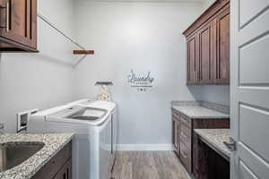 Laundry room featuring cabinet space, light wood-style flooring, and washing machine and dryer