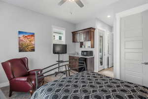 Bedroom featuring ceiling fan, beverage cooler, and light colored carpet