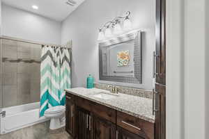 Bathroom featuring vanity, shower / bathtub combination with curtain, dark wood-style floors, and recessed lighting