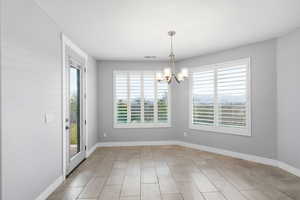 Unfurnished dining area featuring baseboards and a chandelier