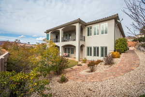 Back of property featuring stucco siding, a patio, a balcony, and a tiled roof
