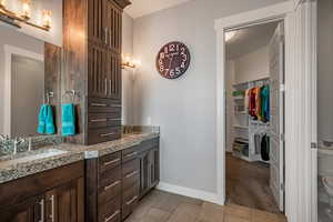 Bathroom featuring double vanity, a spacious closet, light tile patterned flooring, and light colored carpet