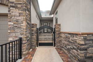 Entrance to property with stone siding, a gate, and stucco siding