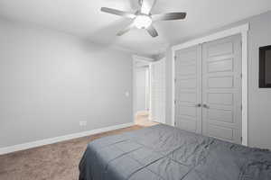 Carpeted bedroom featuring a ceiling fan and a closet
